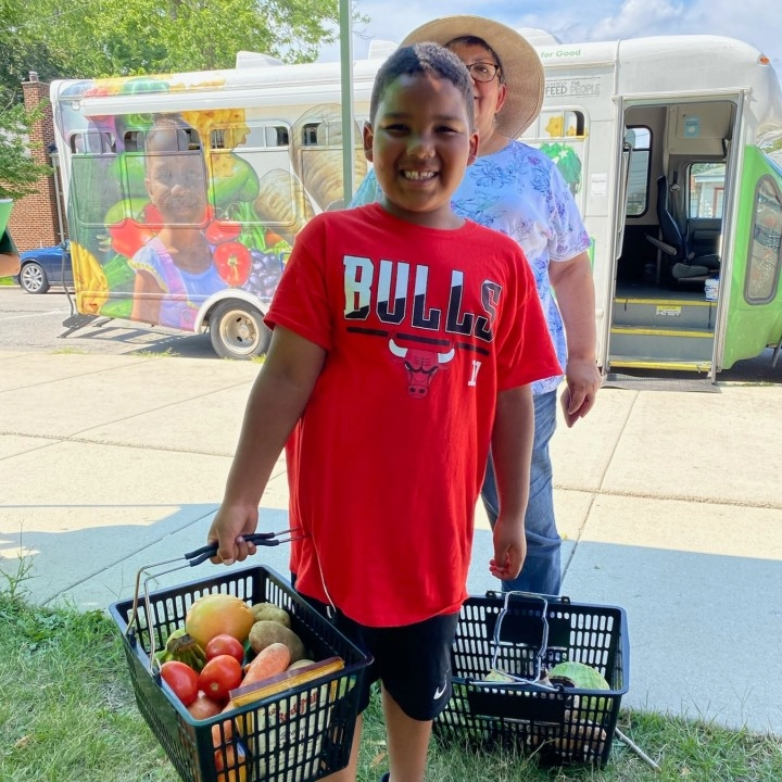 A pre-teen and his mother carry produce in a basket